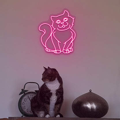 Wall decor with a pink LED cat neon sign glowing on the wall and a cute cat below.