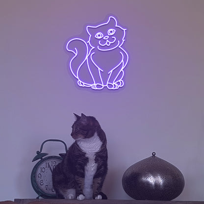 Image of a cat LED neon sign hanging on a wall in purple color above a cute cat.