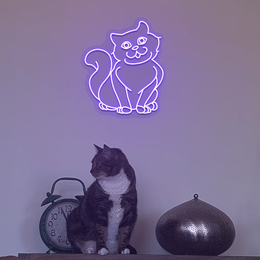 Image of a cat LED neon sign hanging on a wall in purple color above a cute cat.