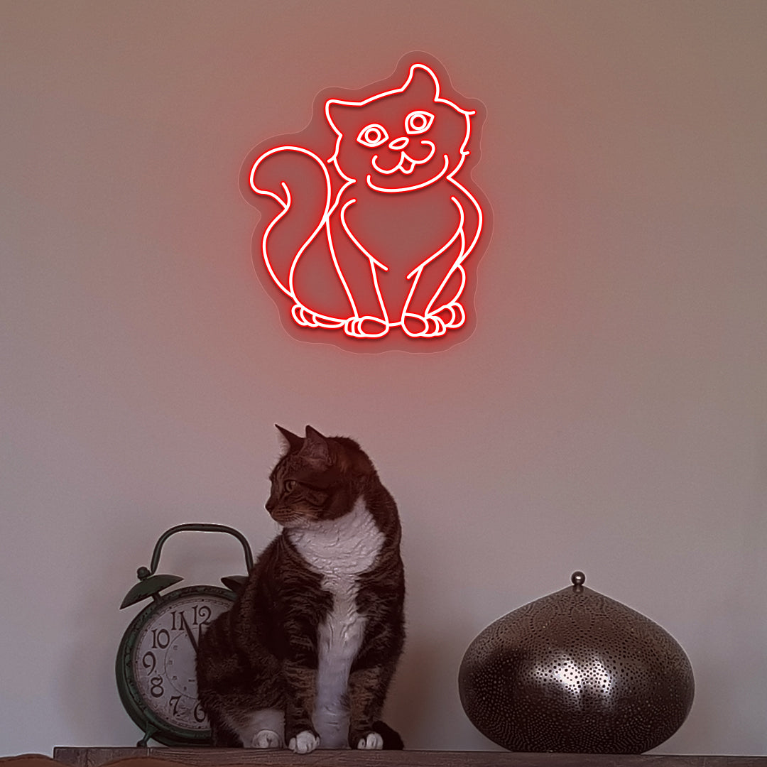 Wall decor with a red LED cat neon sign glowing on the wall and a cute cat below.