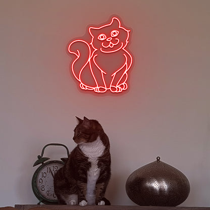 Wall decor with a red LED cat neon sign glowing on the wall and a cute cat below.