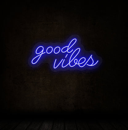 Image of a good vibes neon sign glowing on a dark wall in blue color.