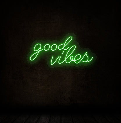 Modern decor with good vibes LED neon sign glowing green on wall.