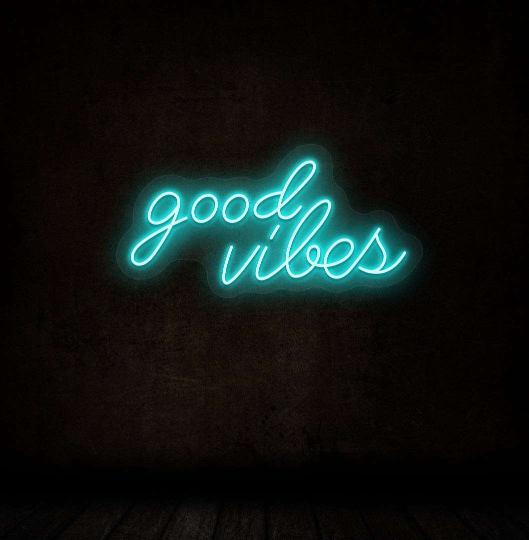 Image of a good vibes neon sign glowing on a dark wall in ice blue color.