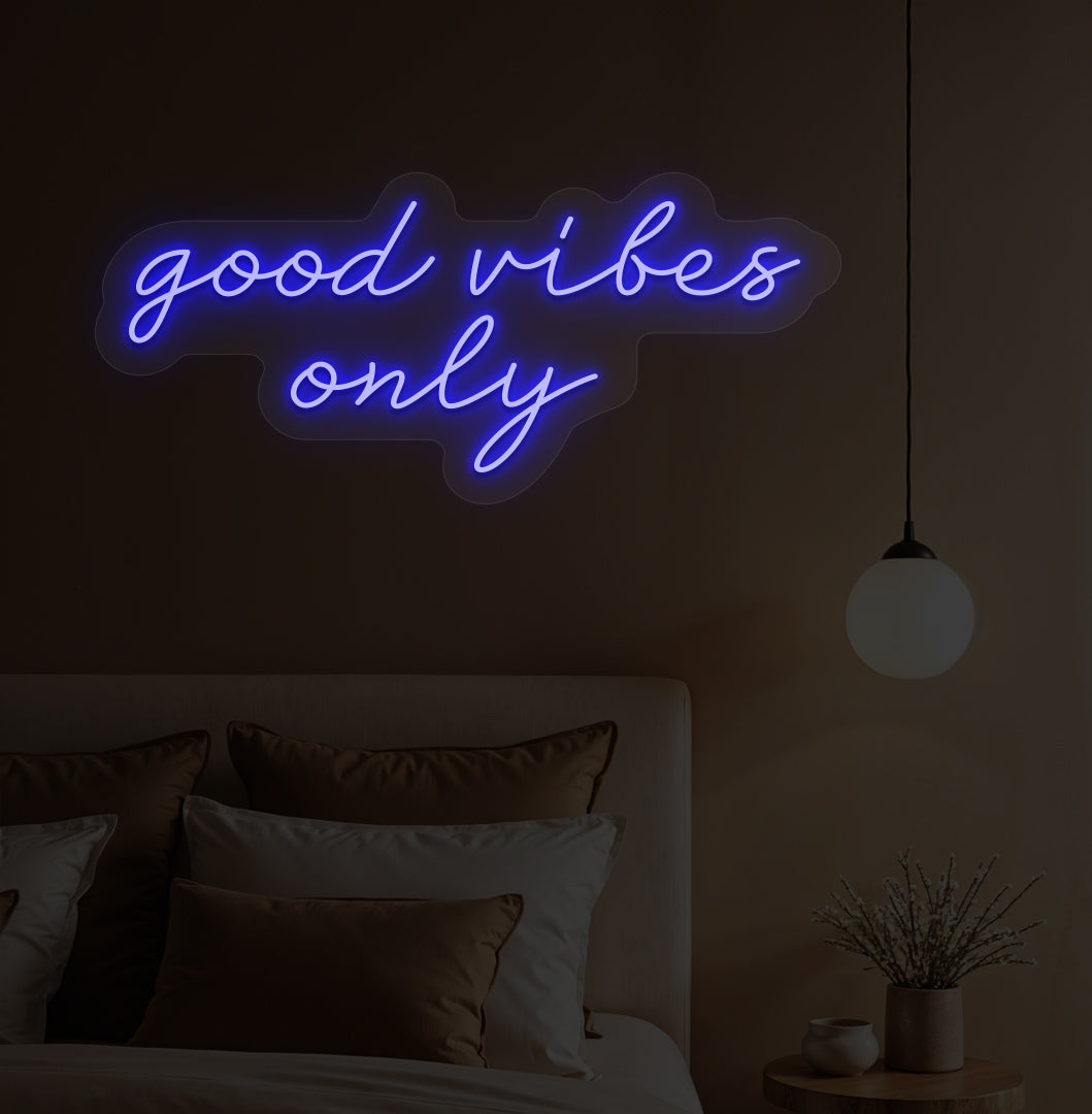Image of a "Good vibes only" blue neon sign hanging on a bedroom wall. 