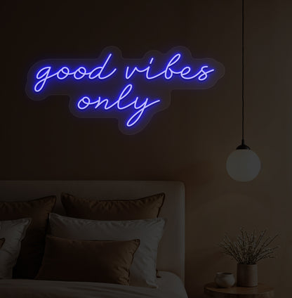 Image of a "Good vibes only" blue neon sign hanging on a bedroom wall. 