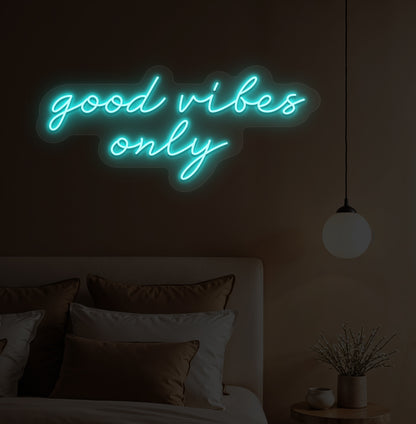 Image of a "Good vibes only" ice blue neon sign hanging on a bedroom wall. 