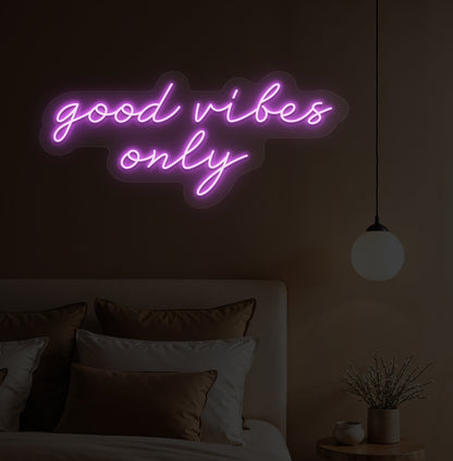 Image of a "Good vibes only" purple neon sign hanging on a bedroom wall. 
