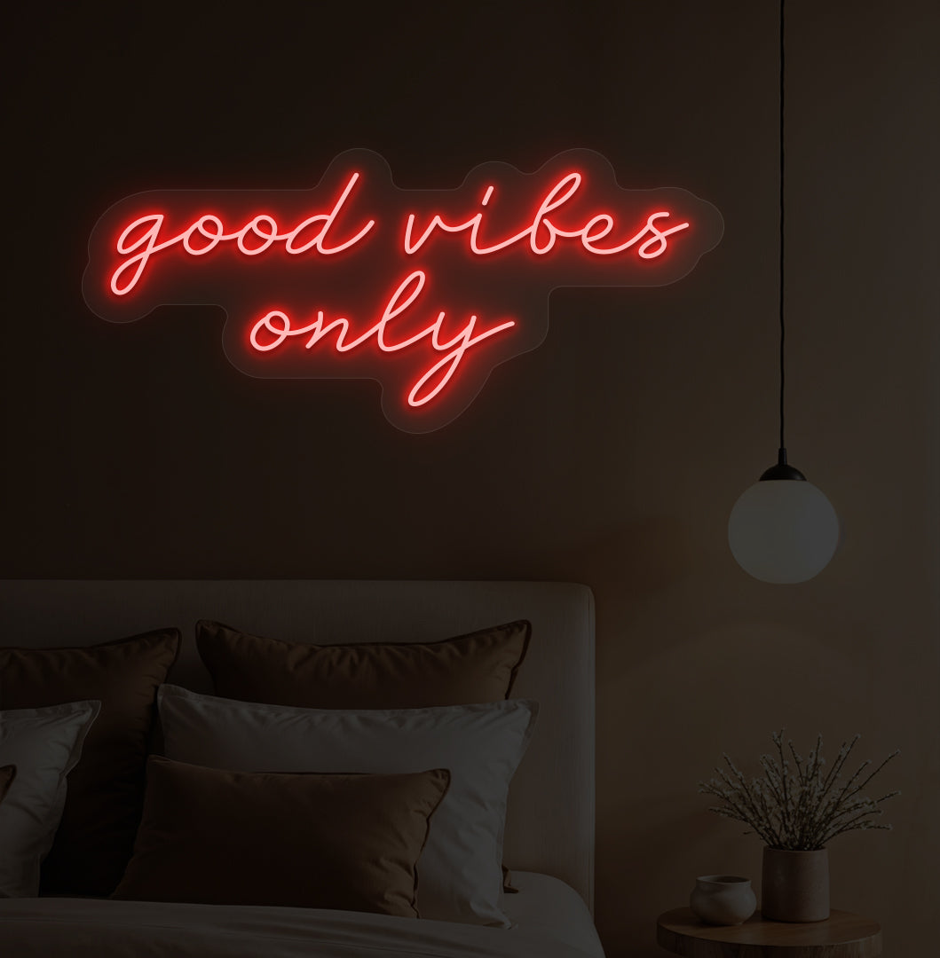 A red LED "good vibes only" neon sign on a bedroom wall with soft lighting.