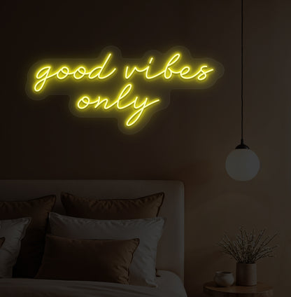 Image of a "Good vibes only" yellow neon sign hanging on a bedroom wall. 