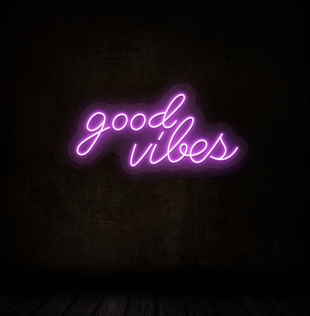 Image of a good vibes neon sign glowing on a dark wall in purple color.
