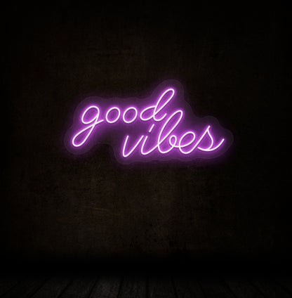 Image of a good vibes neon sign glowing on a dark wall in purple color.