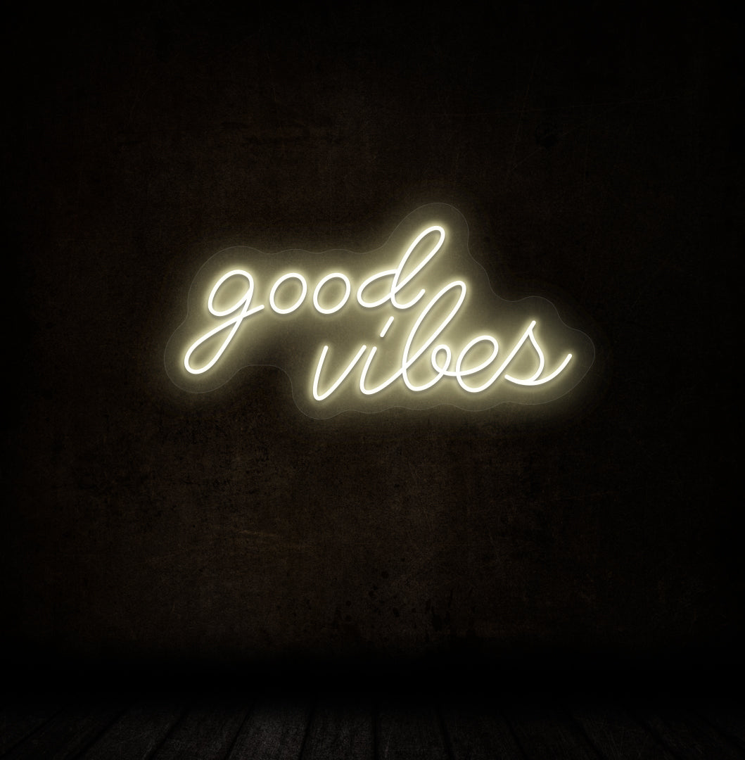 Modern decor with good vibes LED neon sign glowing warm white on wall.