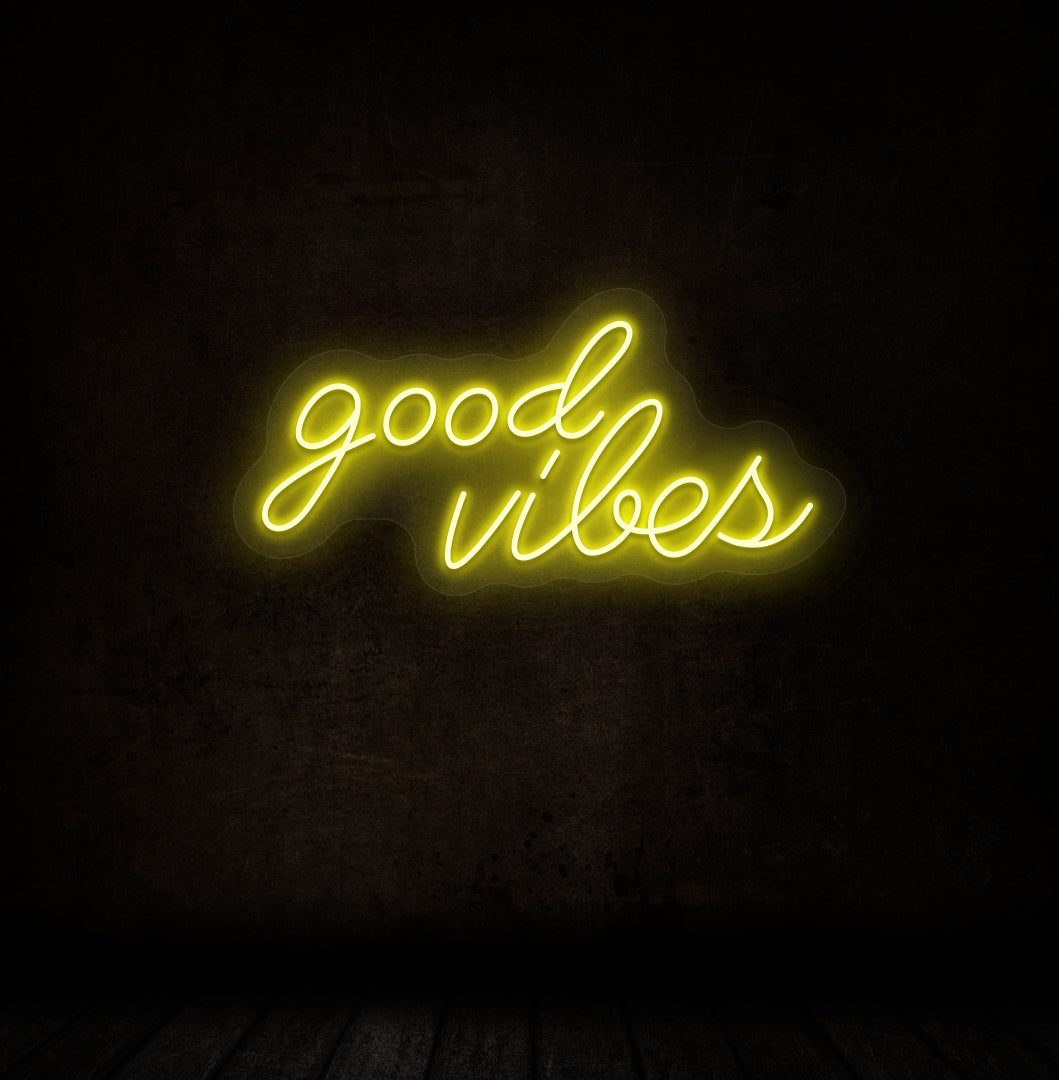 Image of a good vibes neon sign glowing on a dark wall in blue yellow.