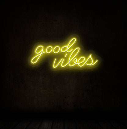 Image of a good vibes neon sign glowing on a dark wall in blue yellow.