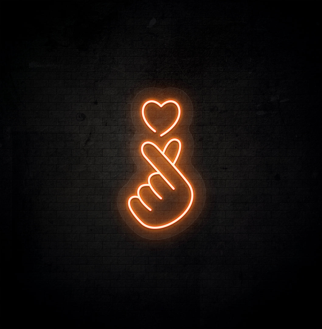 A stylish orange LED hand heart neon sign glowing on a dark background wall.
