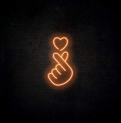 A stylish orange LED hand heart neon sign glowing on a dark background wall.