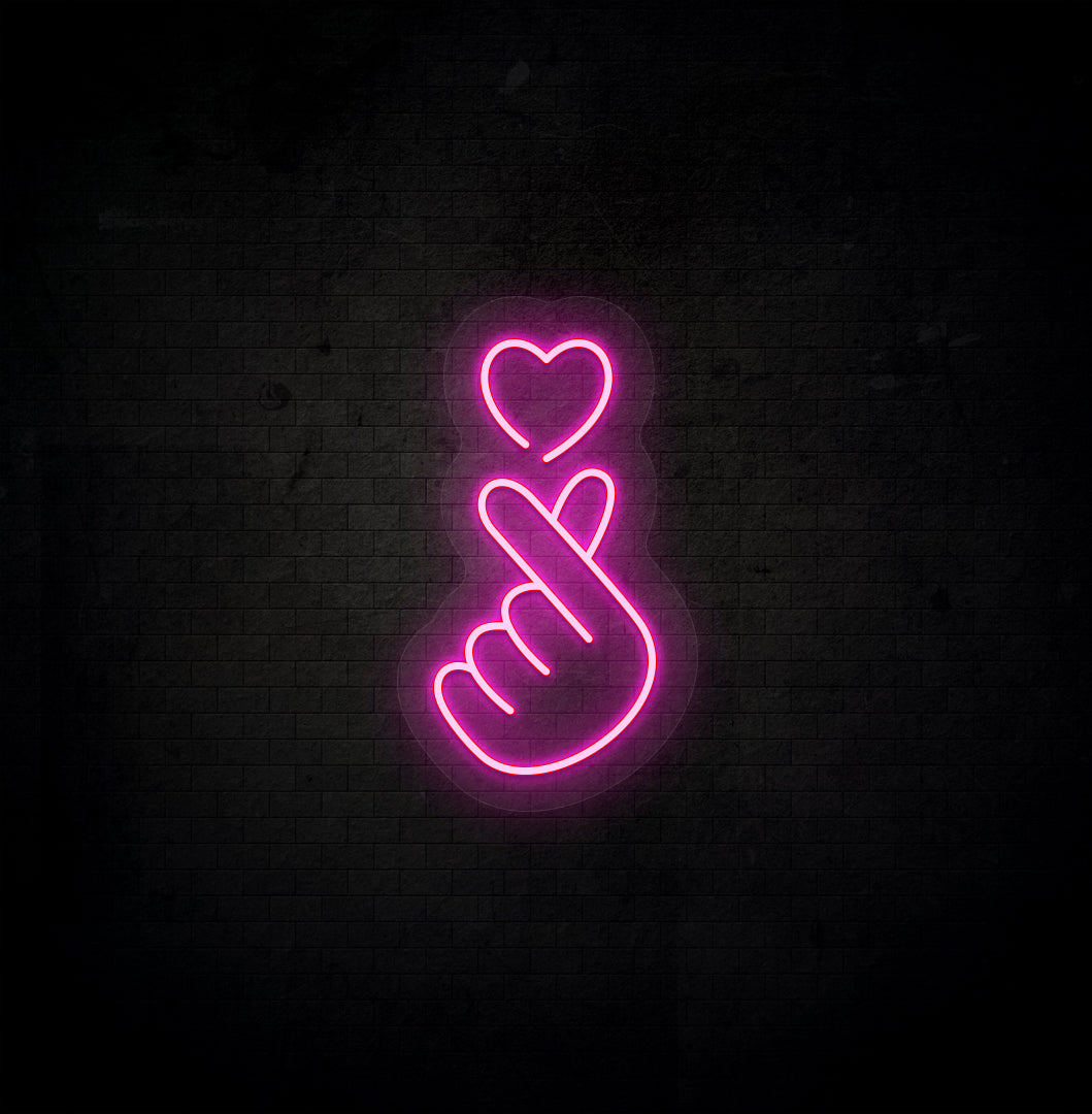 Image of a hand heart LED neon sign mounted on dark wall in pink color.