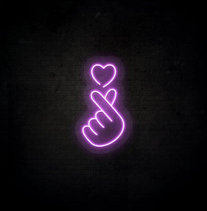 A stylish purple LED hand heart neon sign glowing on a dark background wall.