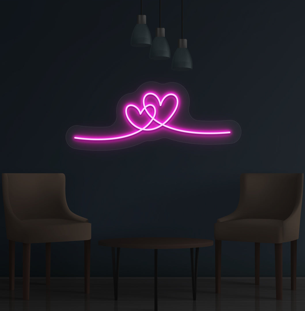 Image of a romantic heart LED neon sign glowing on a wall in pink color.