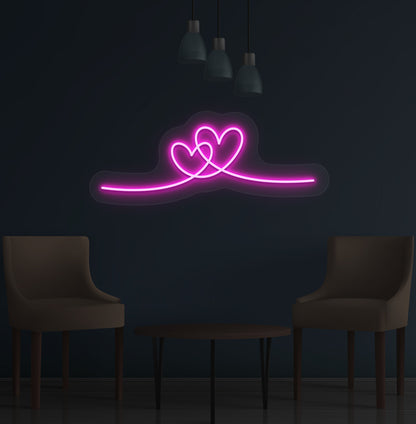 Image of a romantic heart LED neon sign glowing on a wall in pink color.