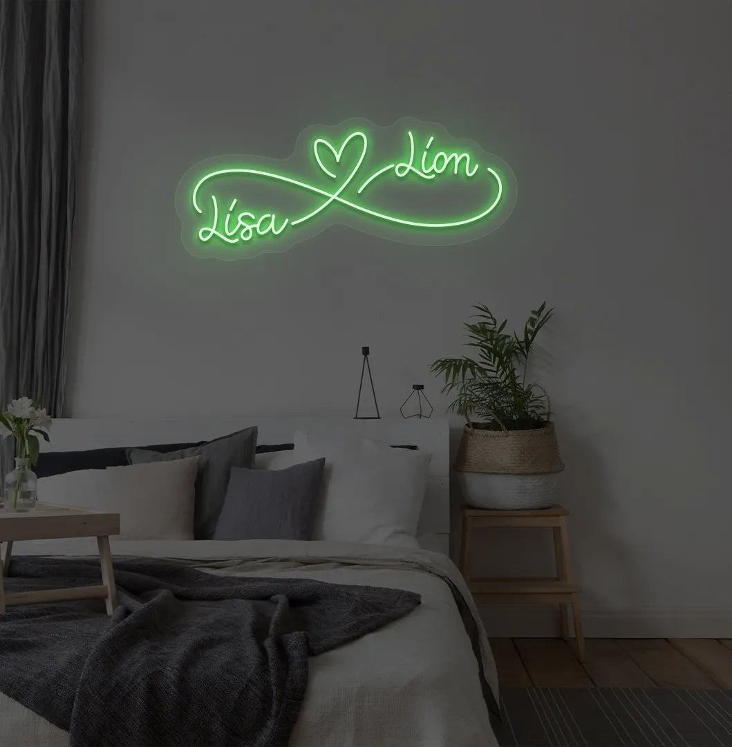 Personalized infinity couple name neon sign mounted on modern bedroom wall in green color.