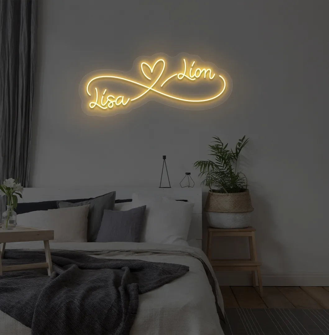 Personalized infinity couple name neon sign mounted on modern bedroom wall in orange color.