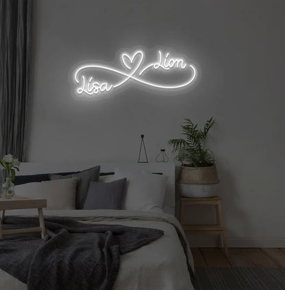 Custom Infinity Couple Name white LED neon sign mounted on bedroom wall.