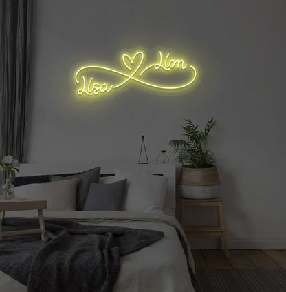 Personalized infinity couple name neon sign mounted on modern bedroom wall in yellow color.