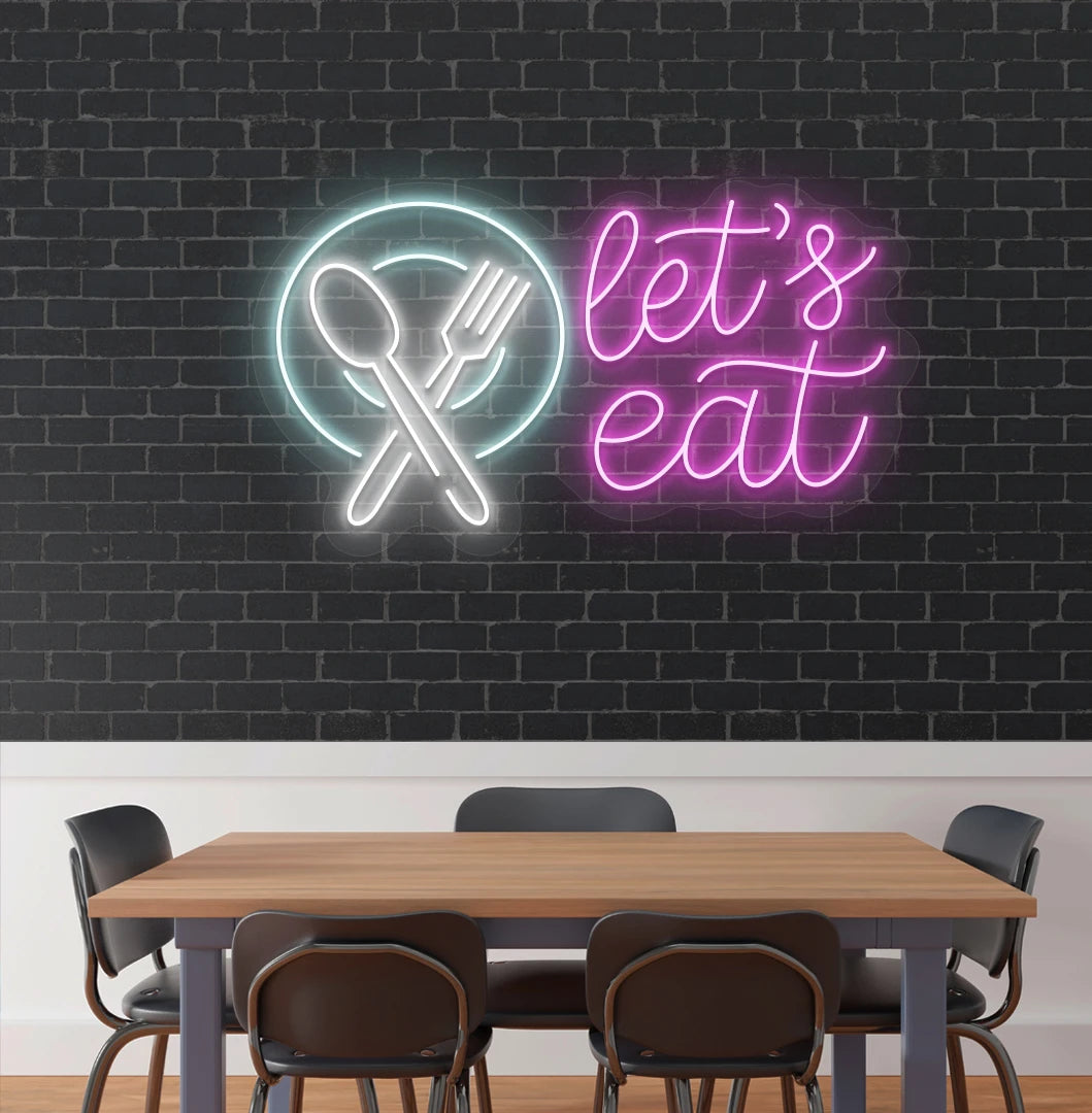 Image of a let’s eat neon sign with plate and cutlery icon glowing on cafe wall in pink color.