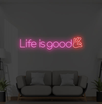Image of a positive "life is good" LED neon sign glowing pink on wall.