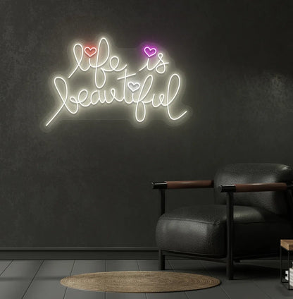 Trendy Life Is Beautiful neon sign mounted on aesthetic bedroom wall in warm white color.