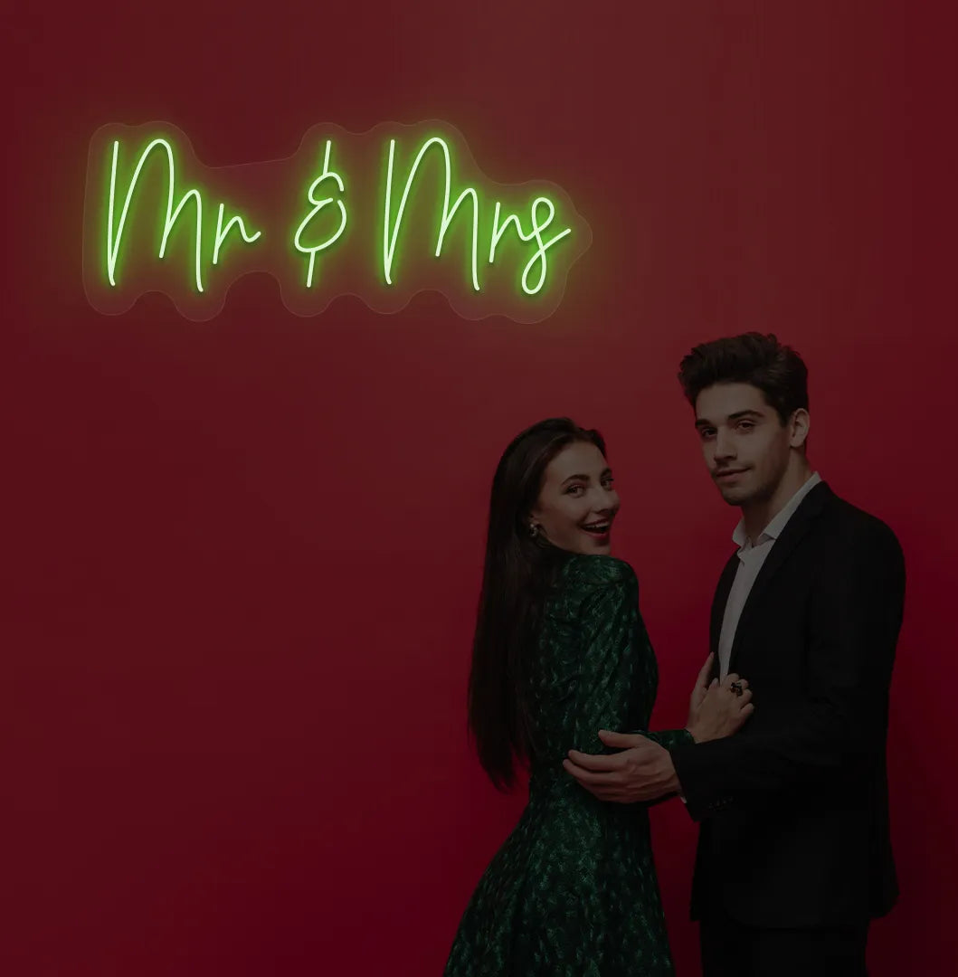 Elegant Mr and Mrs wedding neon sign glowing green on wedding backdrop.