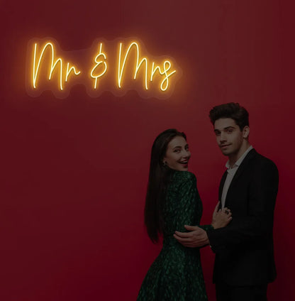 Elegant Mr and Mrs wedding neon sign glowing orange on wedding backdrop.