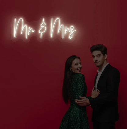 Elegant Mr and Mrs wedding neon sign glowing warm white on wedding backdrop.
