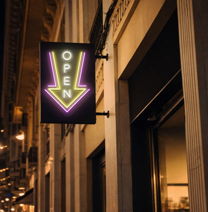Directional open arrow neon sign glowing warm white on outdoor stand.