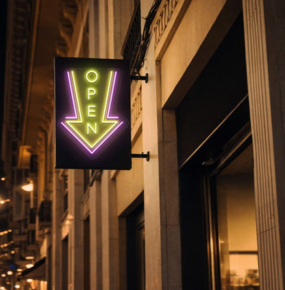 Directional open arrow neon sign glowing yellow on outdoor stand.