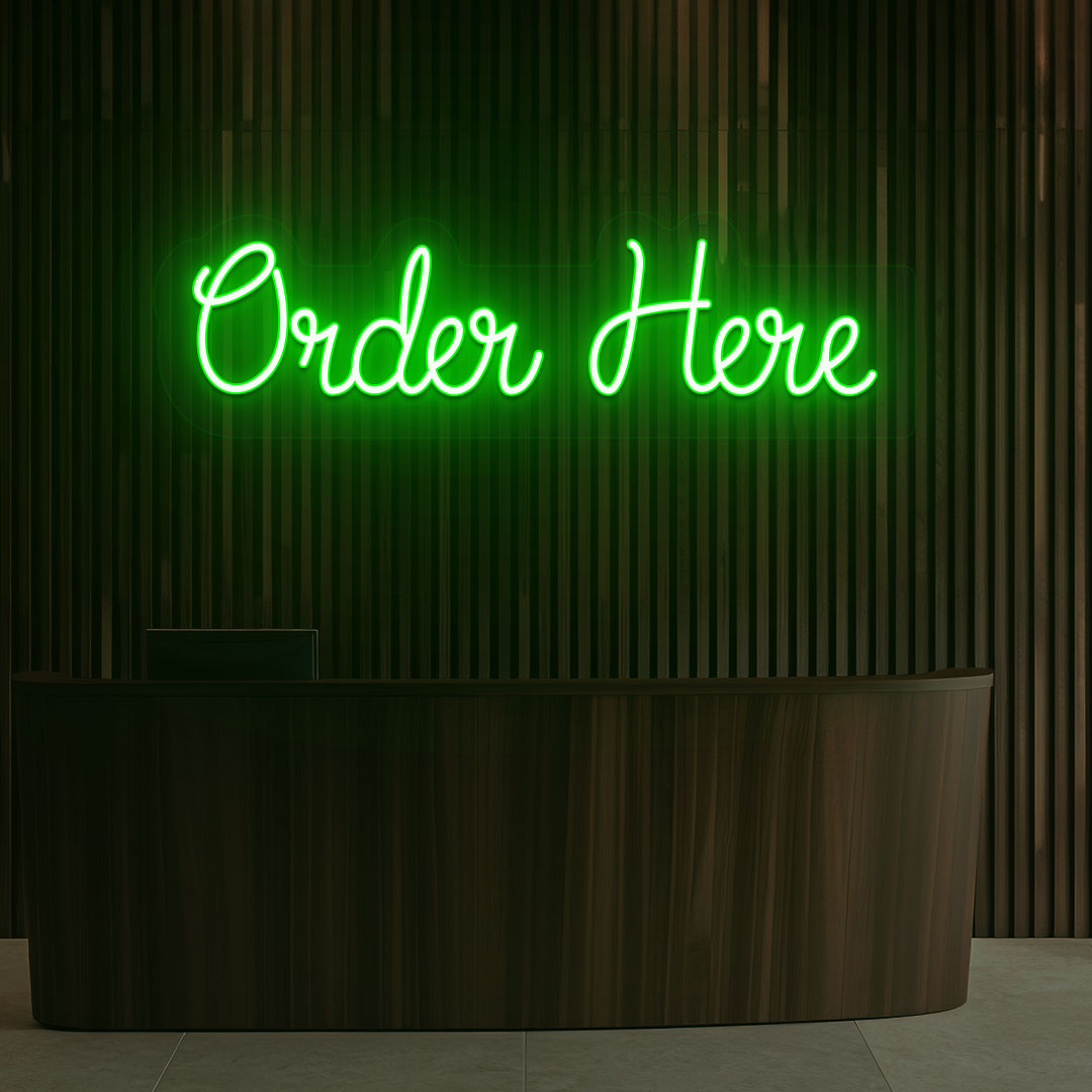 A stylish green LED "order now" neon sign is glowing on the cafe wall above the counter.