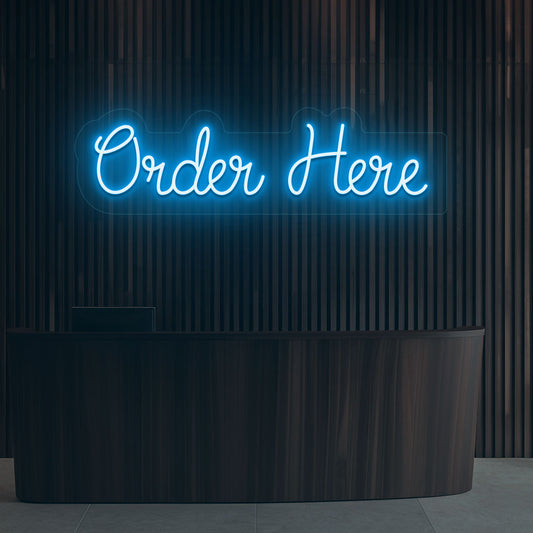 Image of a neon sign that says "order now" glowing in ice blue color on a wooden wall above the counter in a cafe.