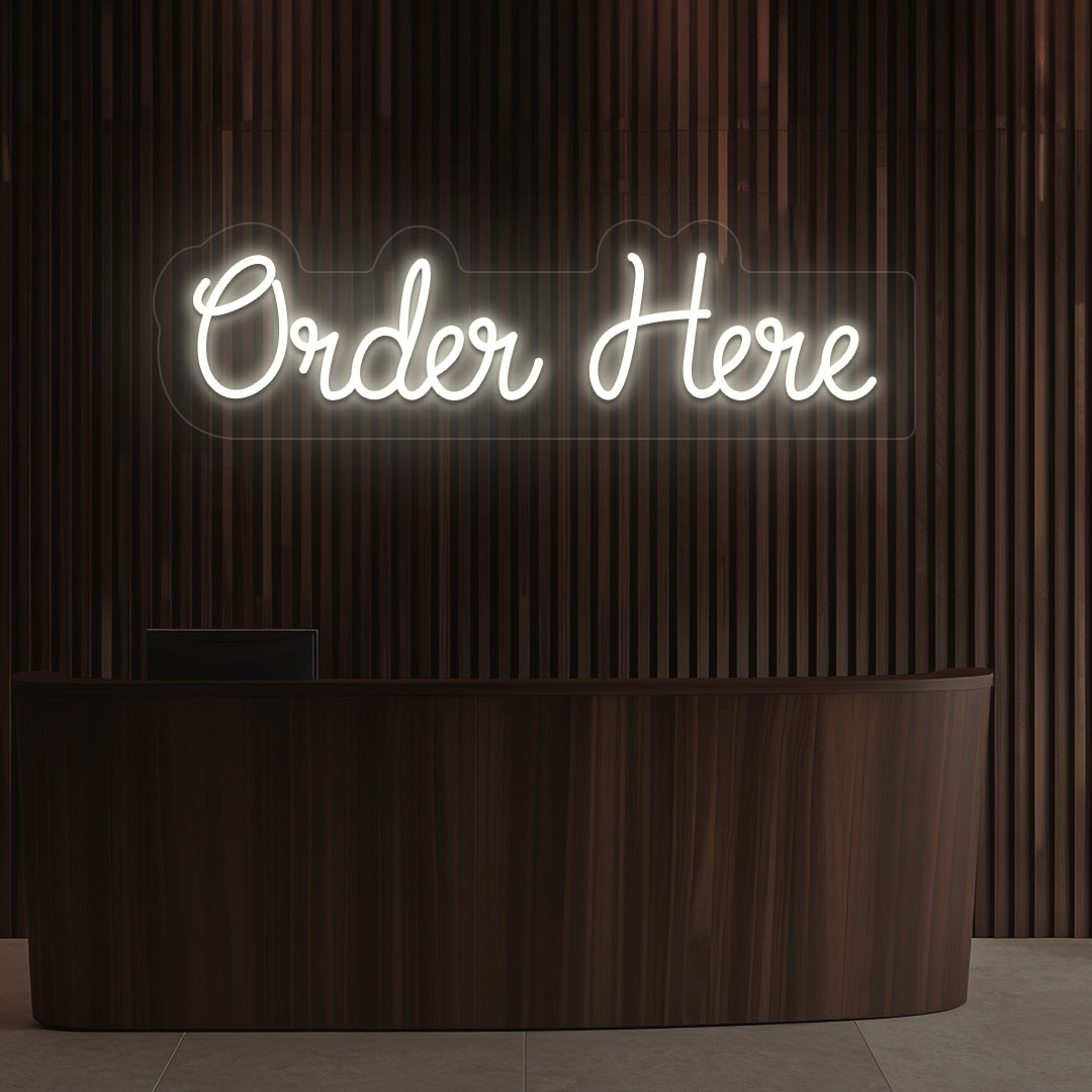 Image of a neon sign that says "order now" glowing in warm white color on a wooden wall above the counter in a cafe.