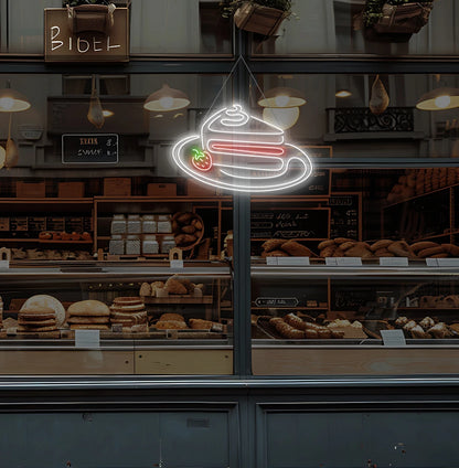 Modern cake shop entrance with pastry neon sign glowing white.