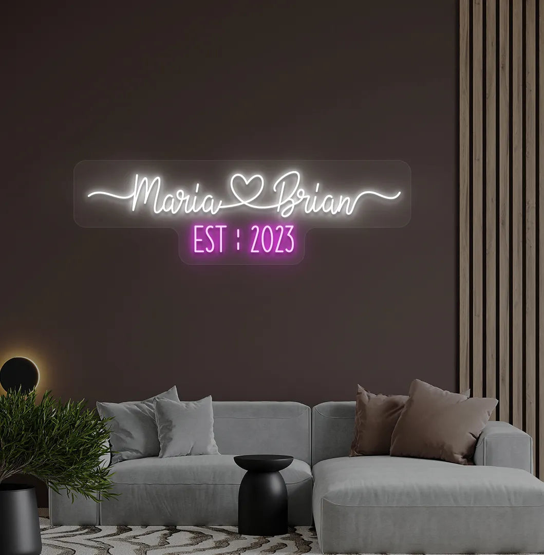 Romantic custom Couple Name EST neon sign glowing white on aesthetic wall.