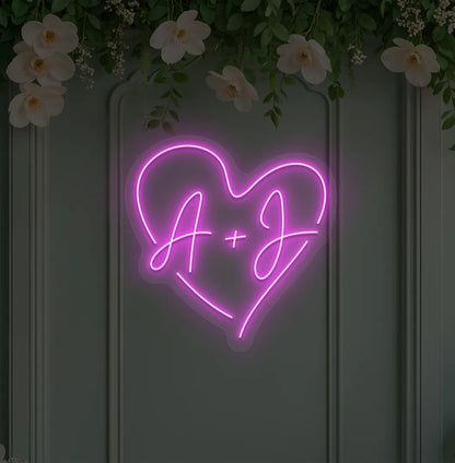 Personalized wedding initials neon sign glowing pink on wedding backdrop.