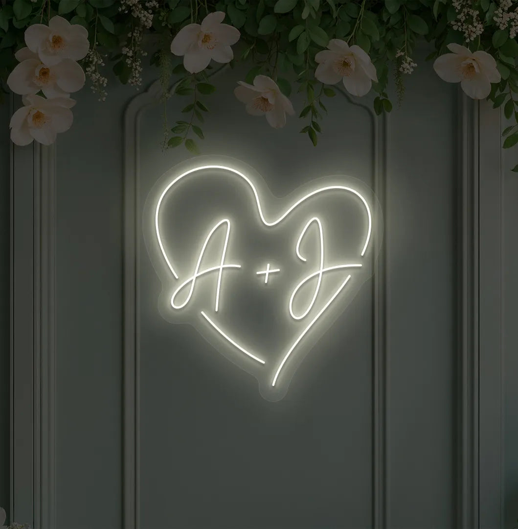 Image of a personalized wedding initials neon sign glowing warm white on decorative wall.