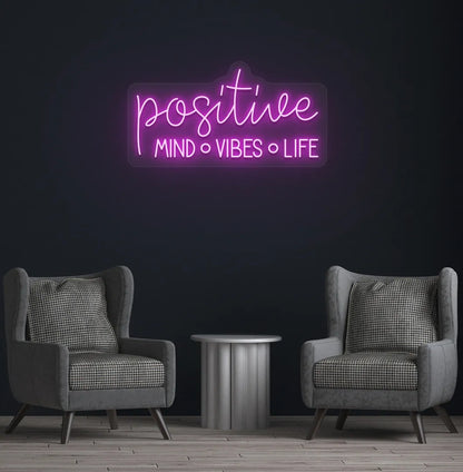 Stylish Positive Mind Vibes Life neon sign mounted on aesthetic room wall in purple color.