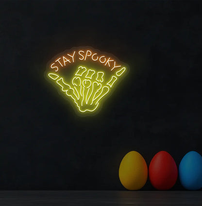 Skeleton Hand Orange Neon Sign creating a spooky glow on a Halloween themed wall.