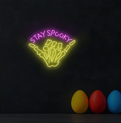 Pink Skeleton Hand Neon Sign glowing on a spooky Halloween themed wall.