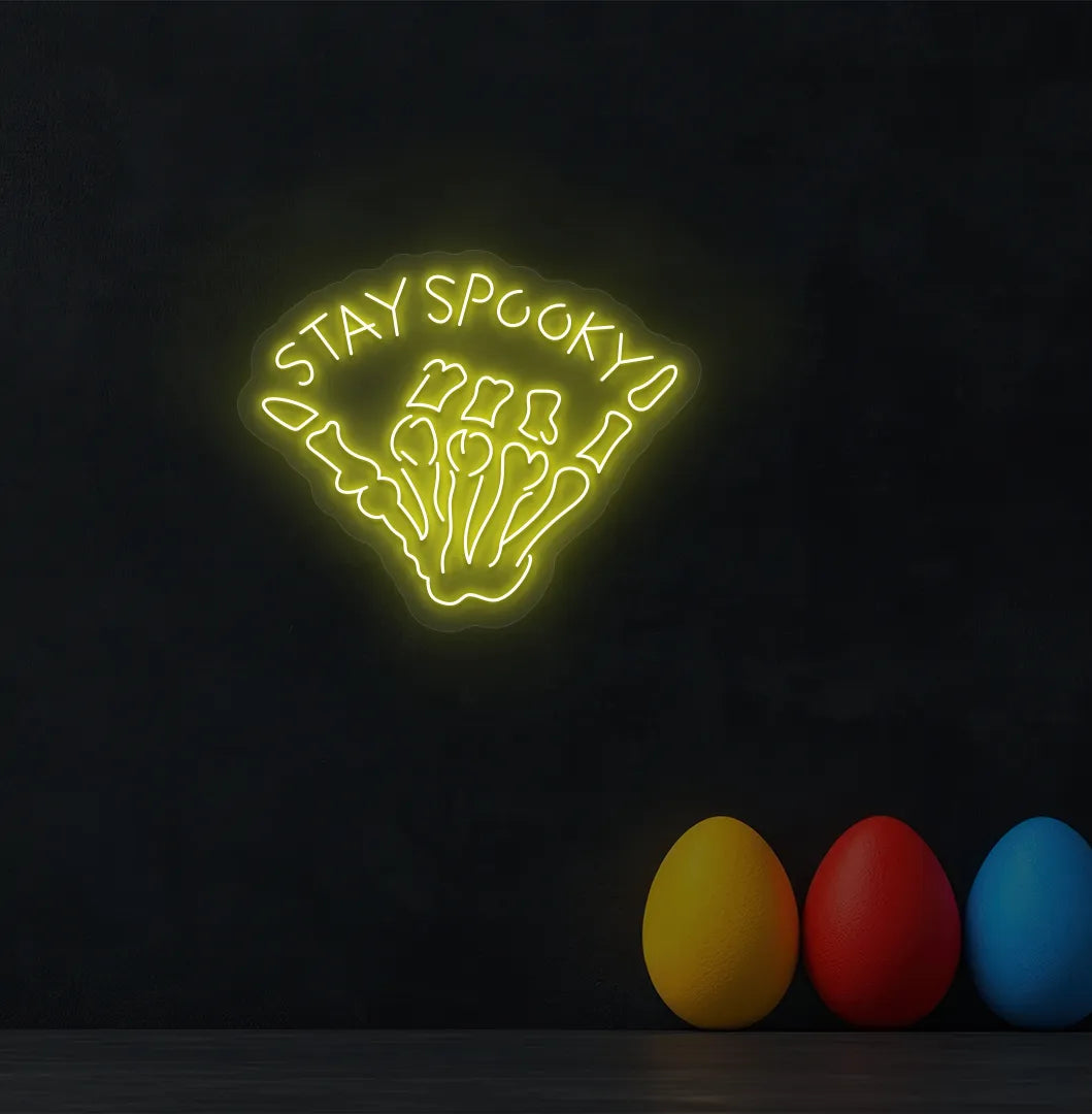Skeleton Hand Yellow Neon Sign creating a spooky glow on a Halloween themed wall.