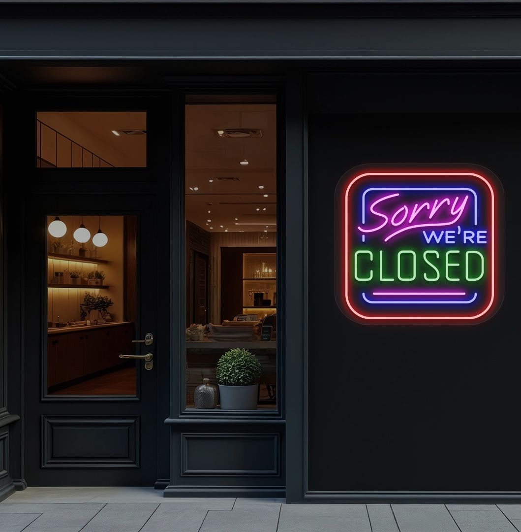 Storefront wall with sorry we're closed neon sign glowing green. 