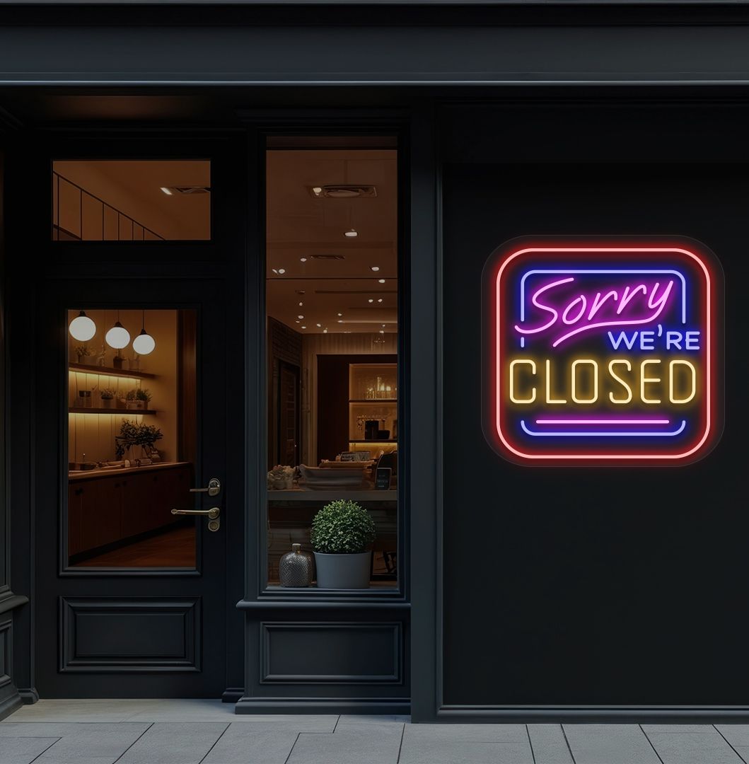 Storefront wall with sorry we're closed neon sign glowing orange. 